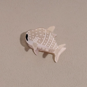 Détail d'une pince à cheveux en forme de baleine en acétate aux motifs géométriques