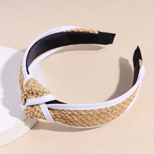 Detail of hand-woven straw headband with white fabric trim and stylish center knot design