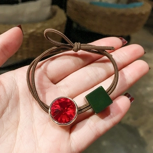 Elastic hair tie and bracelet featuring red crystal and green square charm accents