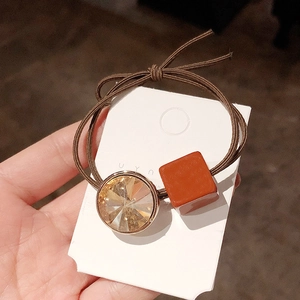 Close-up of double-strand hair tie with amber crystal and caramel square ornament