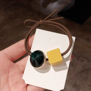 Detail of elastic hair tie with green faceted crystal and yellow square bead charms