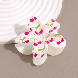 Détail de la pince à cheveux en forme de fleur avec imprimé cerise sur résine crème