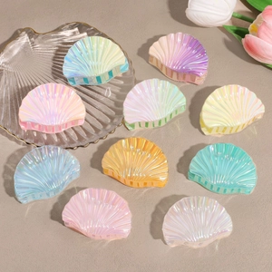 Iridescent shell-shaped hair claws in various macaron colors on a neutral background