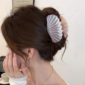 Detail view of shell-shaped hair claw with pearlescent finish on elegant hairstyle