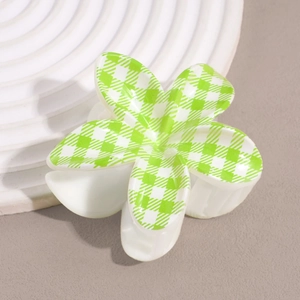 Detail of flower hair claw clip with green and white checkered pattern on a ceramic tray