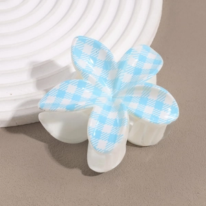 Close-up of blue houndstooth pattern on white flower-shaped hair claw clip accessory