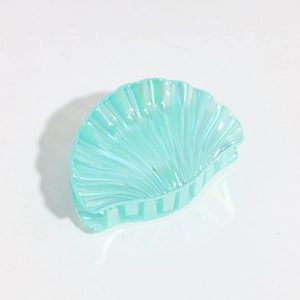 Detail view of shell-shaped hair claw with iridescent mint green finish and pearl texture