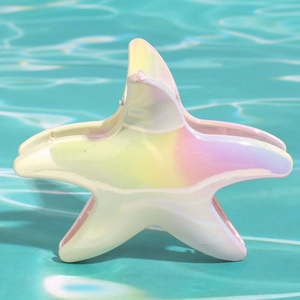 Dettaglio del fermaglio a stella marina iridescente su sfondo d'acqua blu frizzante