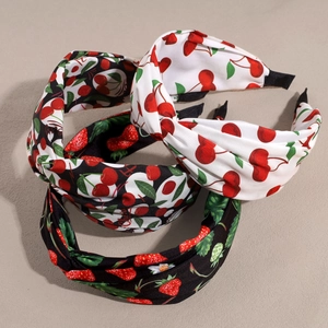 Detail view of twisted wide headbands with cherry and strawberry prints on soft fabric