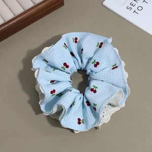 Detail of blue plaid scrunchie with red cherry embroidery and white lace edges