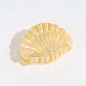 Detailed view of yellow shell-shaped hair claw with iridescent pearly finish and strong grip