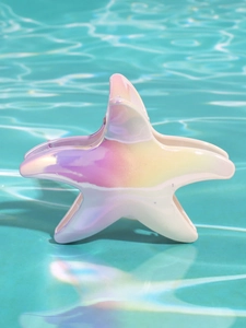 Vista macro di un fermaglio per capelli a forma di stella marina iridescente sull'acqua della piscina