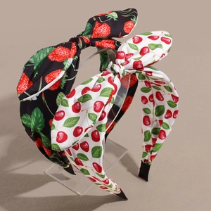 Detail of satin headbands featuring cherry and strawberry prints with large bow accents