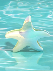 Dettaglio di un fermaglio per capelli a forma di stella marina perlata vicino a una piscina