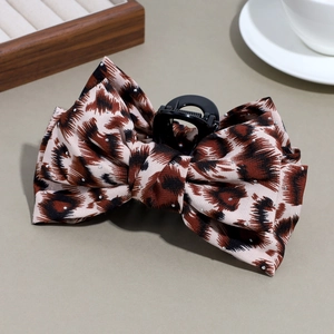Detailed macro shot of a leopard print bow hair claw clip with shiny silver rhinestones