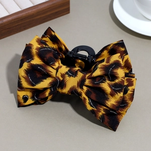 Detail of leopard print bow hair claw clip with silver glitter thread and plastic base