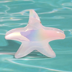Dettaglio della clip per capelli a stella marina iridescente su sfondo d'acqua blu
