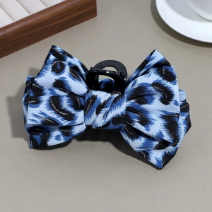 Detail of blue leopard print bow hair claw clip with golden threads and plastic teeth