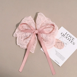Close-up of pink floral lace bow hair clip with detailed mesh embroidery and satin ribbon
