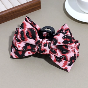 Detail showing pink leopard print fabric bow hair claw clip with subtle silver glitter threads