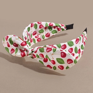 Detail of white cotton headband featuring red cherry prints and a cute bow tie knot