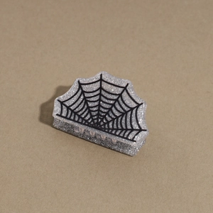 Detail of silver Halloween hair claw with spider web pattern and glitter finish