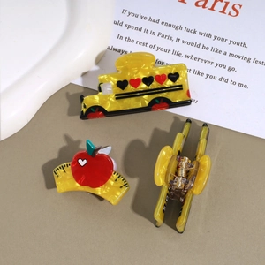 Detailed macro view of yellow school bus and apple ruler hair claw clips with marble texture