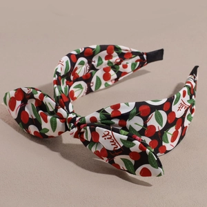 Detail shot of fabric headband featuring cherry print and a large stylish bow decoration