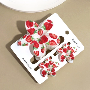 Dettaglio di fermagli per capelli con stampa fragola su cartoncino con vista a 45 gradi