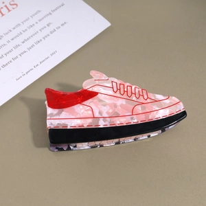 Detailed top view of a pink sneaker-shaped acrylic hair claw clip on a minimalist background