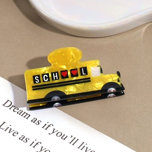 Detail shot of the yellow school bus hair claw clip with school heart engraving
