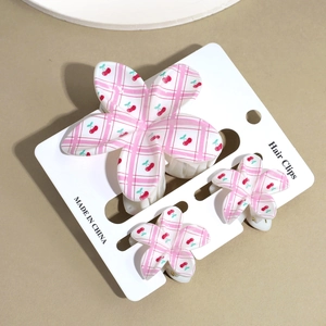 Dettaglio di fermagli per capelli a scacchi rosa con stampe di ciliegie su scheda