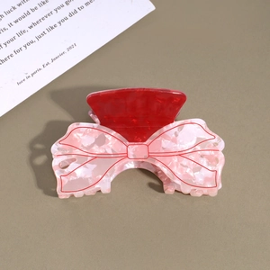 Detailed view of dark red acrylic hair claw clip with floral pattern and bow design
