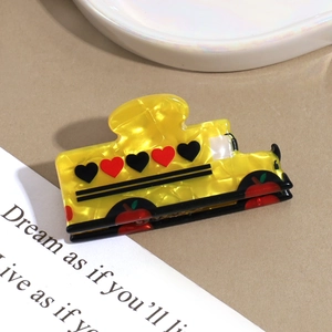 Detail showing yellow acrylic hair claw clip with red hearts and apple patterns