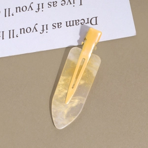 Detail view of yellow acetate duckbill hair clip with marble texture and gold glitter