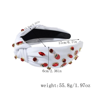 Detail of white fabric knotted headband with red rhinestones and strawberry charms