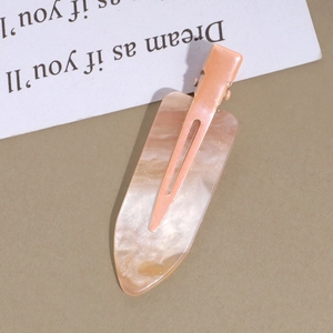 Detail of peach pink hair clip with pearlescent texture and gold glitter sparkles
