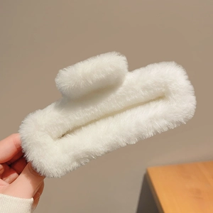 Gros plan sur la pince à cheveux en peluche blanche montrant sa texture douce et sa forme