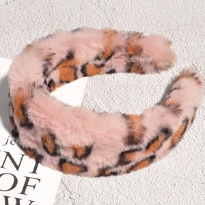 Detailed close-up of pink leopard print plush headband with soft faux fur texture