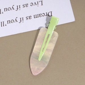 Close-up of pink marble resin duckbill hair clip with vibrant green metal base