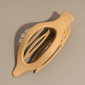 Close-up of matte apricot duckbill hair clip showing oval hollow design and inner teeth