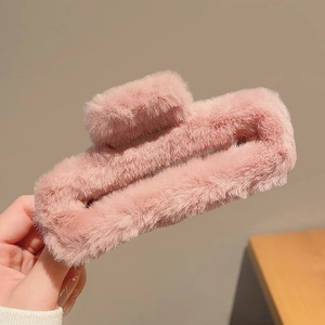 Gros plan sur une grande pince à cheveux carrée en peluche rose texture douce