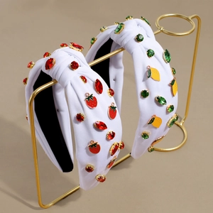 Close-up of knot headbands featuring rhinestone strawberry and lemon charms on a metal stand