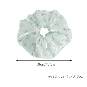Detail view of a green floral scrunchie with butterfly patterns and white rhinestones