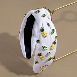 Detail of white fabric headband with green rhinestones and yellow pineapple charms