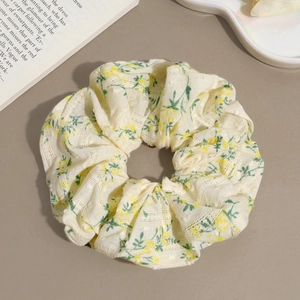 Detail shot of a yellow floral scrunchie with lace trim on a decorative tray