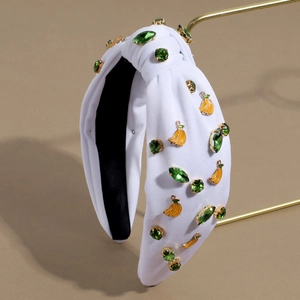 Detail of white knotted headband with green crystals and small yellow banana charms