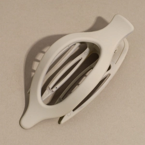 Close-up of a matte beige oval hair claw clip with a hollow geometric design