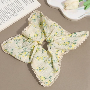 Floral yellow fabric scrunchie with lace trim and large bow design in elegant setting