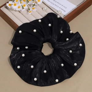 Détail d'un chouchou en organza noir avec fils argentés scintillants et perles blanches